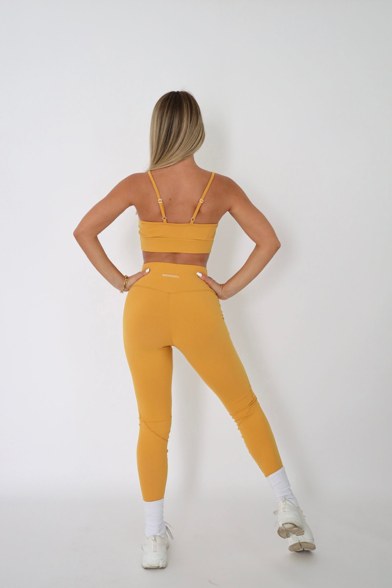 woman wearing mustard sports bra posing from behind