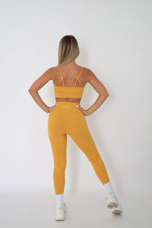 woman wearing mustard sports bra posing from behind
